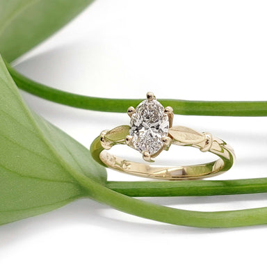 Lab diamond engagement ring in yellow gold with leaf motif, styled with green plant