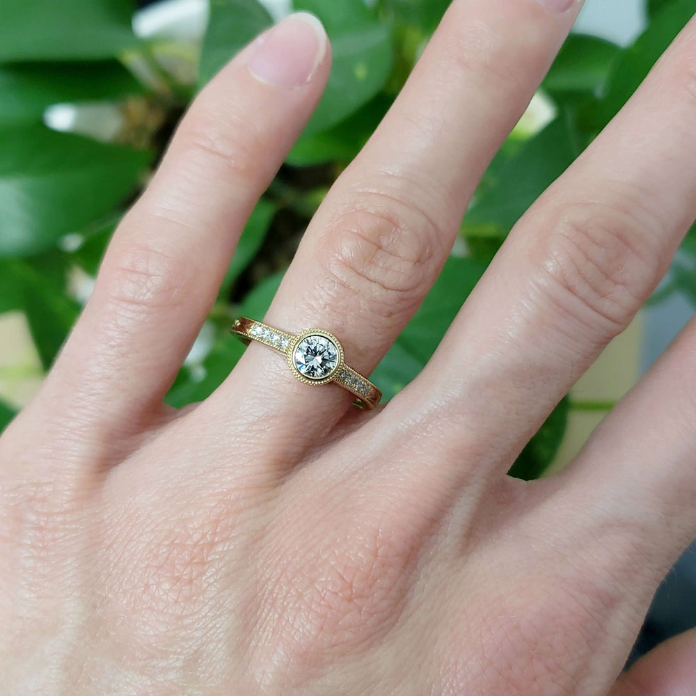 Lab diamond engagement ring in yellow gold, worn on hand with green background