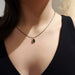 Lab emerald cabochon pendant in 14kt yellow gold with black chain, worn on a model's neck