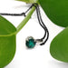Close-up of lab emerald pendant in 14kt white gold with chain and green leaves