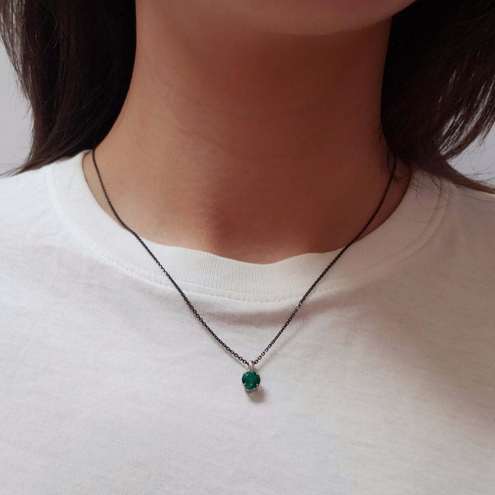 Lab-grown emerald pendant in 14kt white gold worn on a dark chain