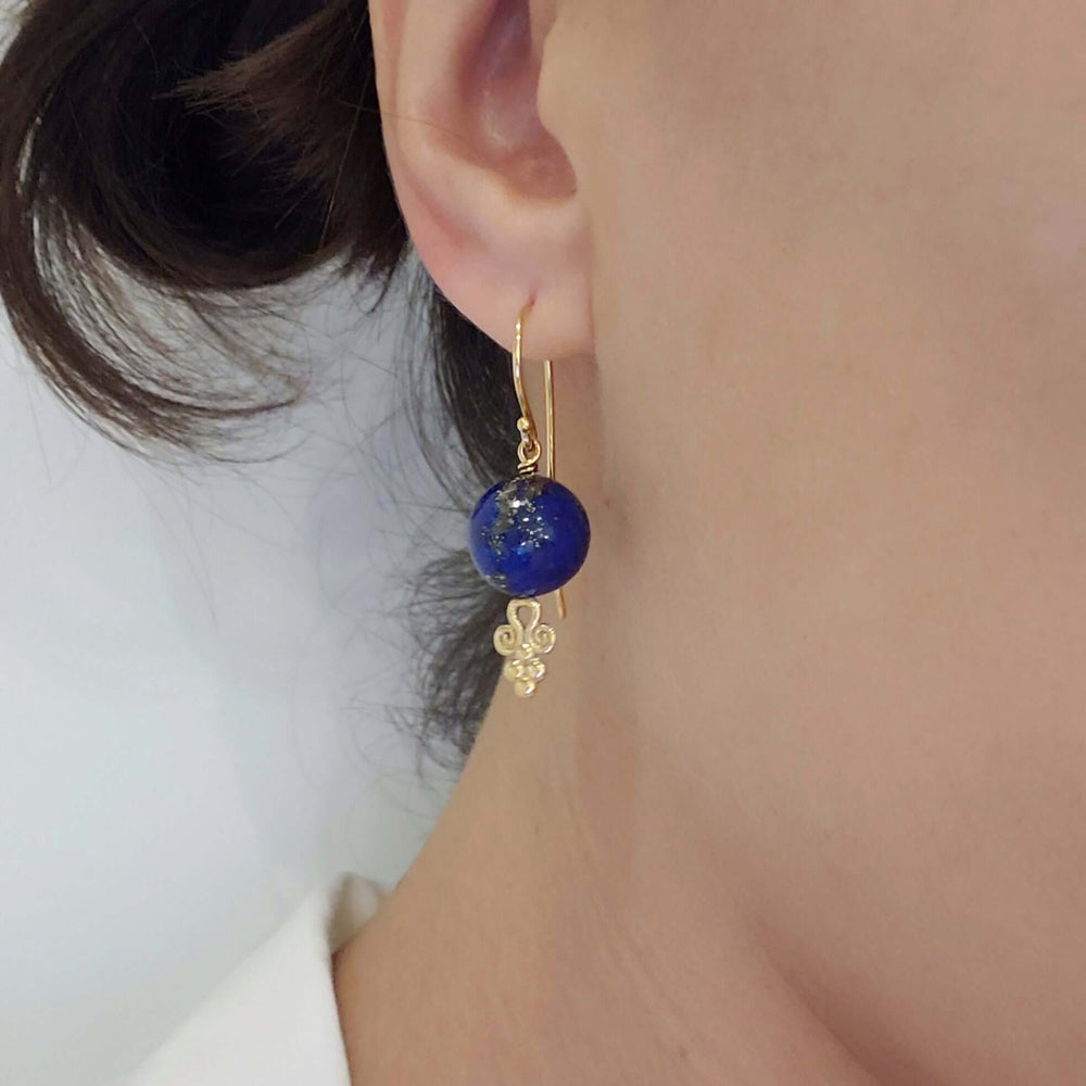 Lapis lazuli and 14kt yellow gold drop earring with scroll accent shown worn on ear