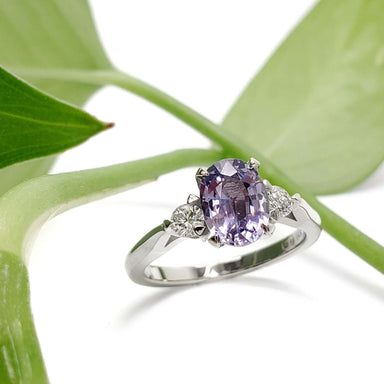Lavender sapphire and lab diamond ring in white gold, displayed on a green leaf