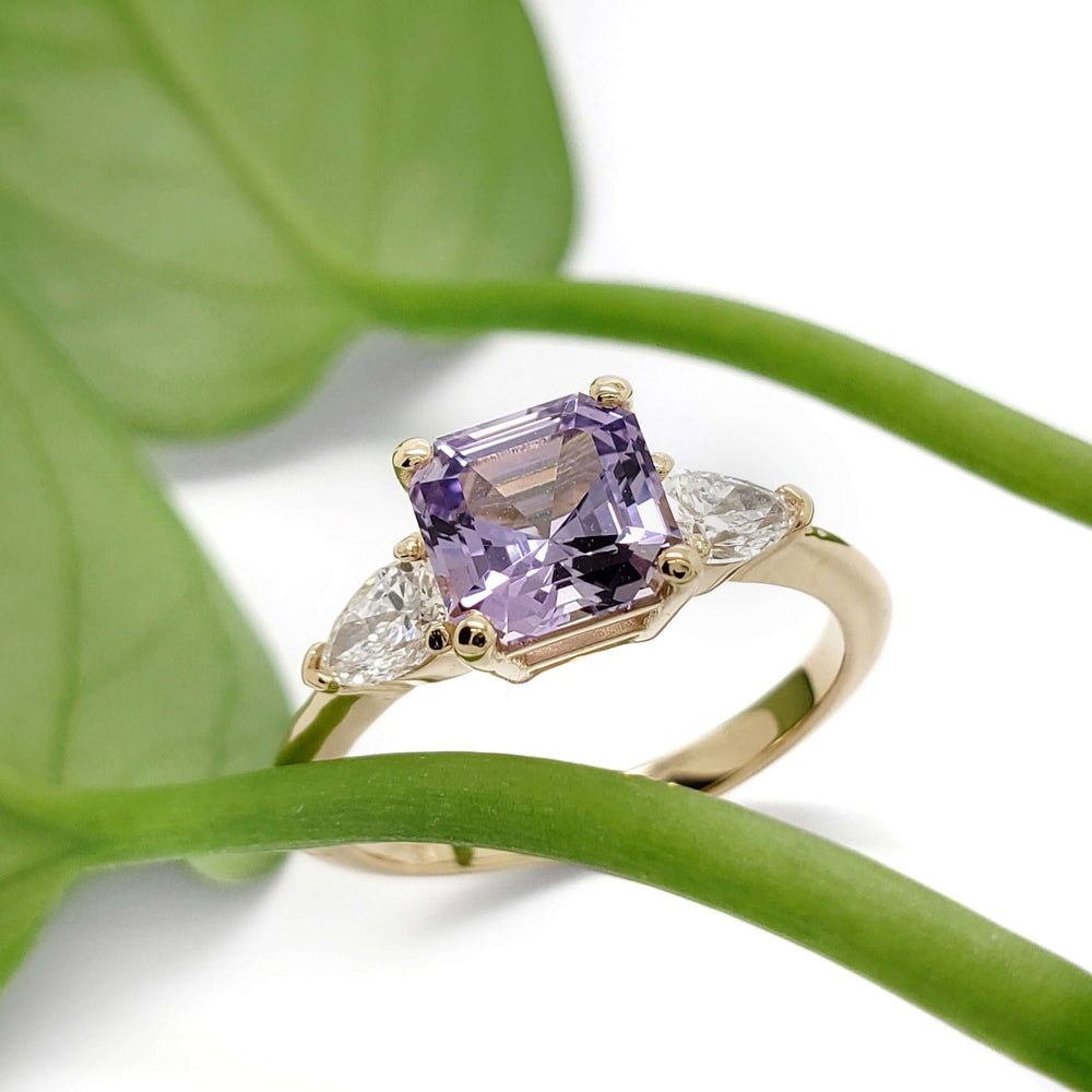 Lavender sapphire and lab diamond ring in yellow gold, shown with green leaf accent