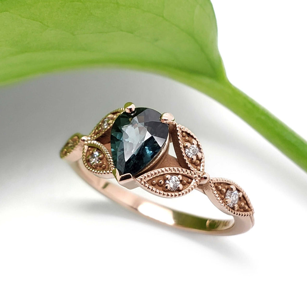 Leaf-inspired 14k rose gold engagement ring with teal sapphire and diamond accents