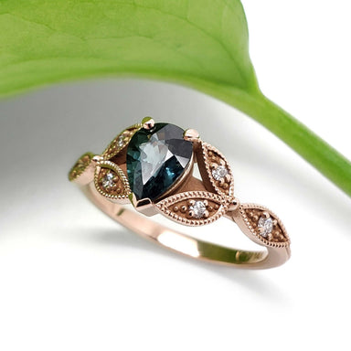 Leaf-inspired 14k rose gold engagement ring with teal sapphire and diamond accents