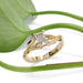 Leaf-inspired 14kt yellow gold lab diamond engagement ring beside green plant