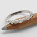 Textured leaf and diamond wedding ring in 14k white gold displayed on a pencil