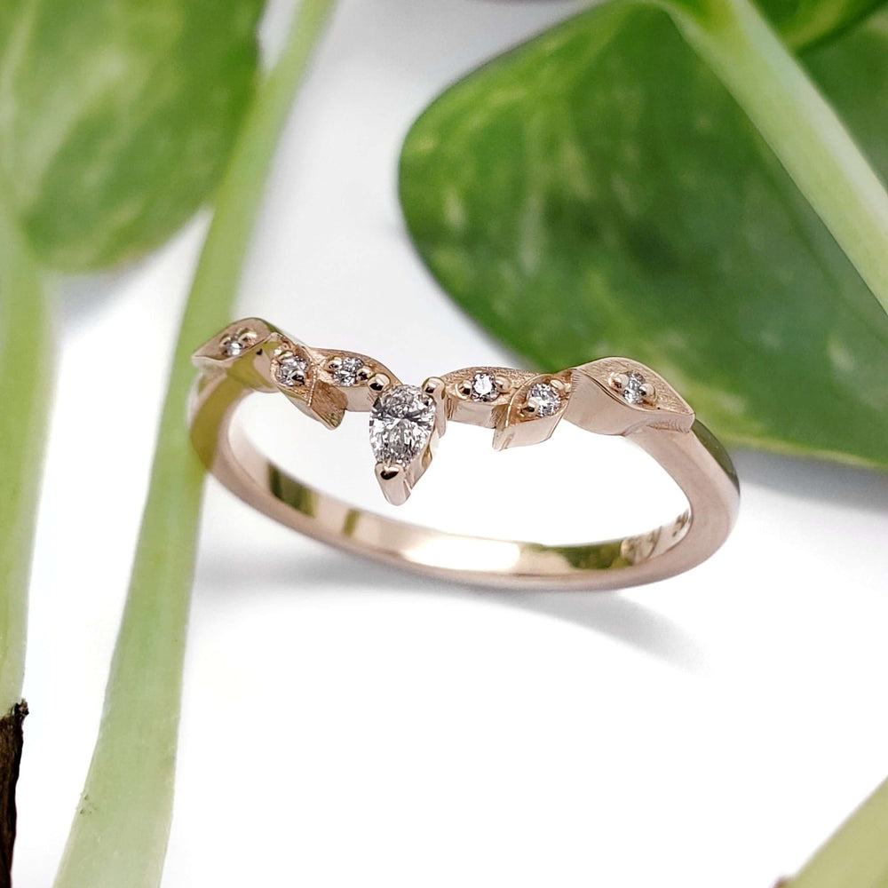 Leafy 14kt rose gold diamond wedding ring shown with green leaves