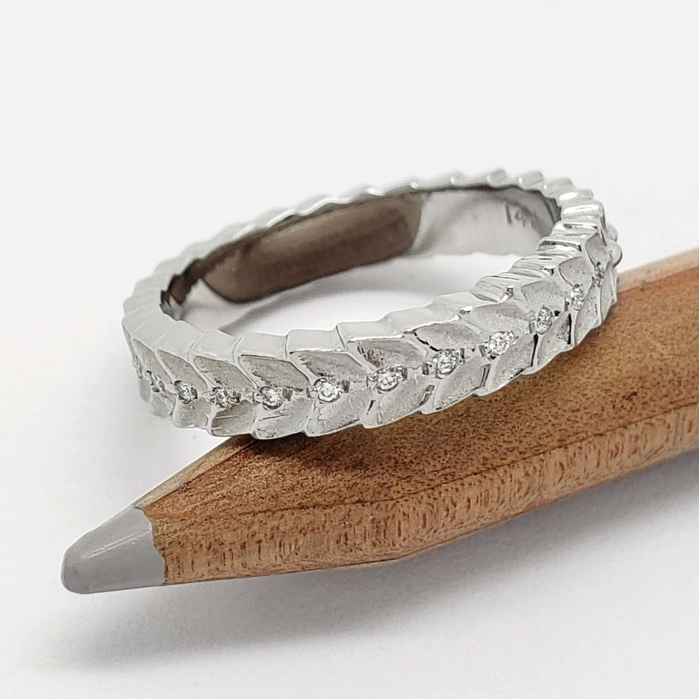 Leafy white gold wedding ring with Canadian diamonds, displayed on pencil