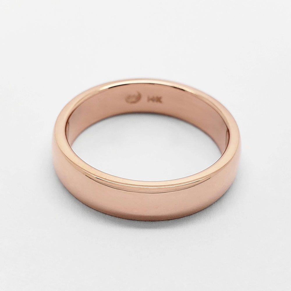 Low dome 14kt rose gold wedding band with comfort fit interior on white background