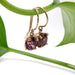 14kt yellow gold drop earrings with oval Madagascar garnets hanging from a green plant stem