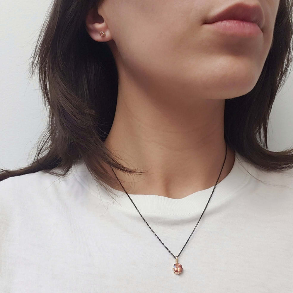 Model wearing Malaya garnet pendant necklace and stud earrings in 14kt yellow gold