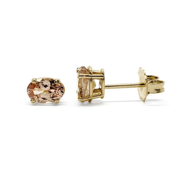Pair of oval peach-pink Malaya garnet stud earrings in 14kt yellow gold on white background