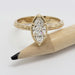 Marquise cut lab diamond engagement ring in yellow gold with engraved band, shown with pencil for scale