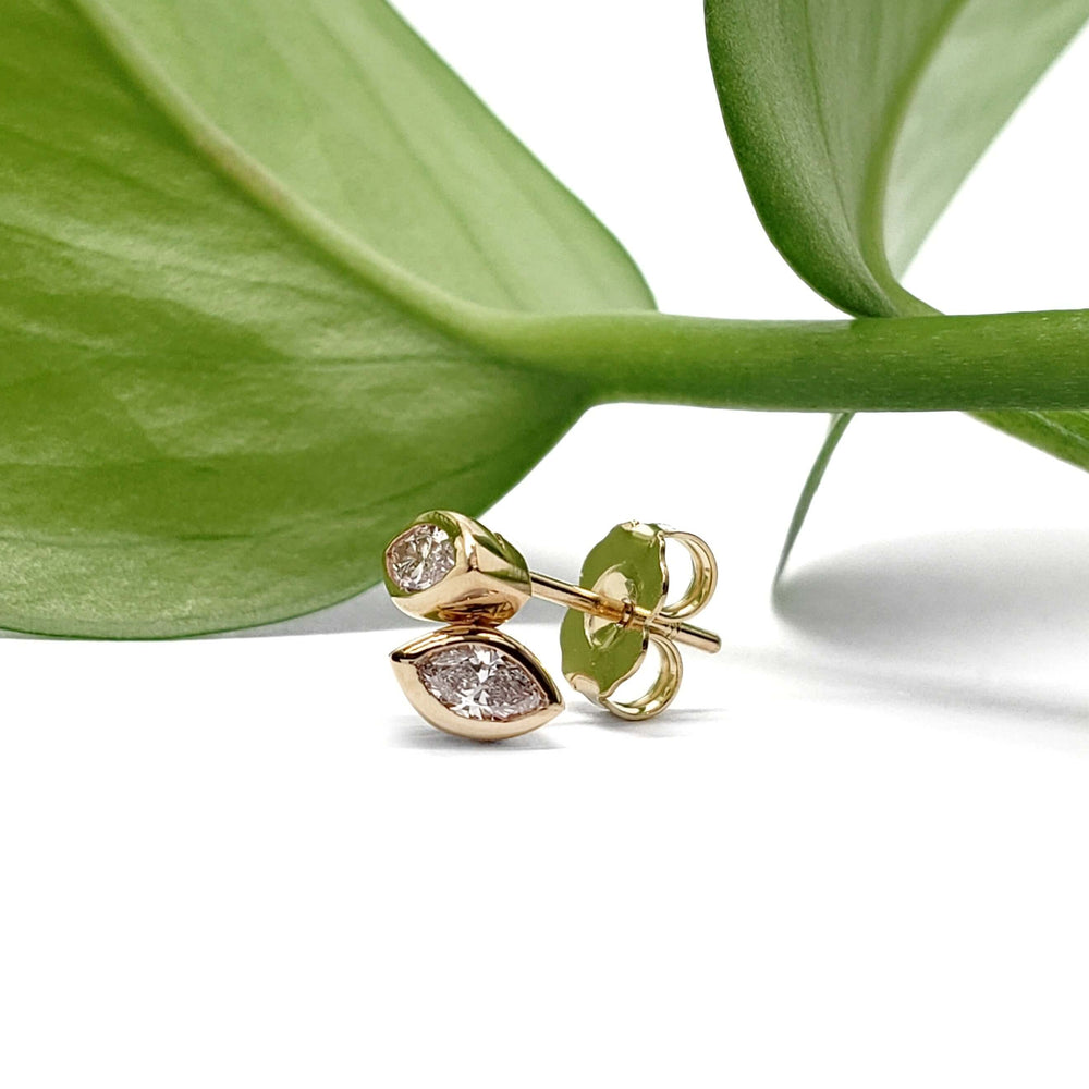 14kt yellow gold marquise diamond bezel stud earrings shown with a green leaf