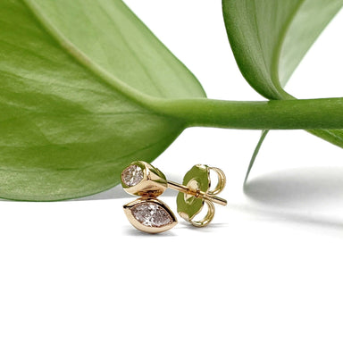 14kt yellow gold marquise diamond bezel stud earrings shown with a green leaf