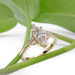 Marquise lab diamond engagement ring in yellow gold resting on green leaves