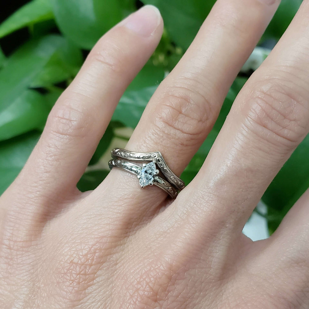 Marquise lab diamond ring with engraved band stacked with chevron band on hand