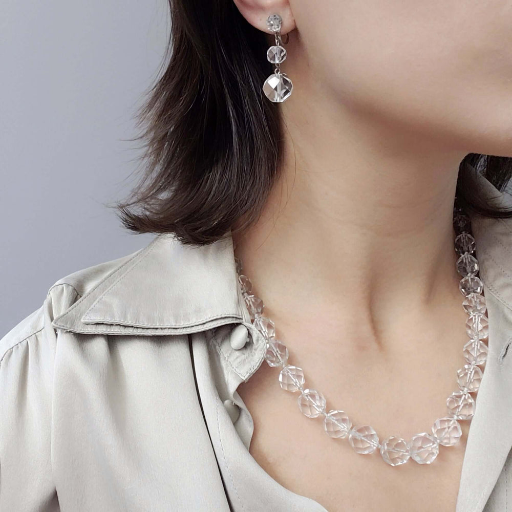 Model wearing faceted clear quartz bead necklace with matching earrings