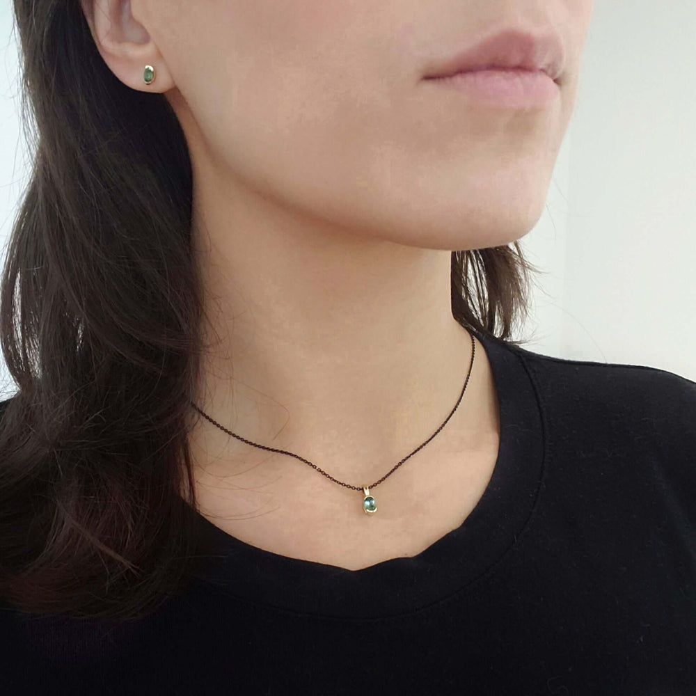Model wearing 14kt yellow gold green tourmaline stud earring and pendant necklace