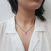 Model wearing 10kt yellow gold lab ruby pendant on a black chain