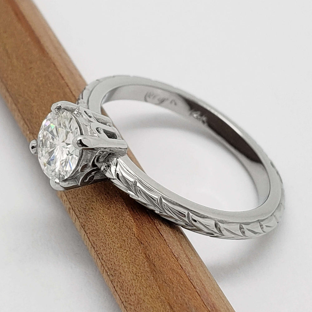 Detailed view of moissanite solitaire ring with wheat engraving on band