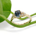 Montana sapphire and diamond engagement ring in 14kt yellow gold beside a green leaf