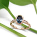 Montana sapphire and diamond engagement ring in 14kt rose gold, shown on white with green leaves
