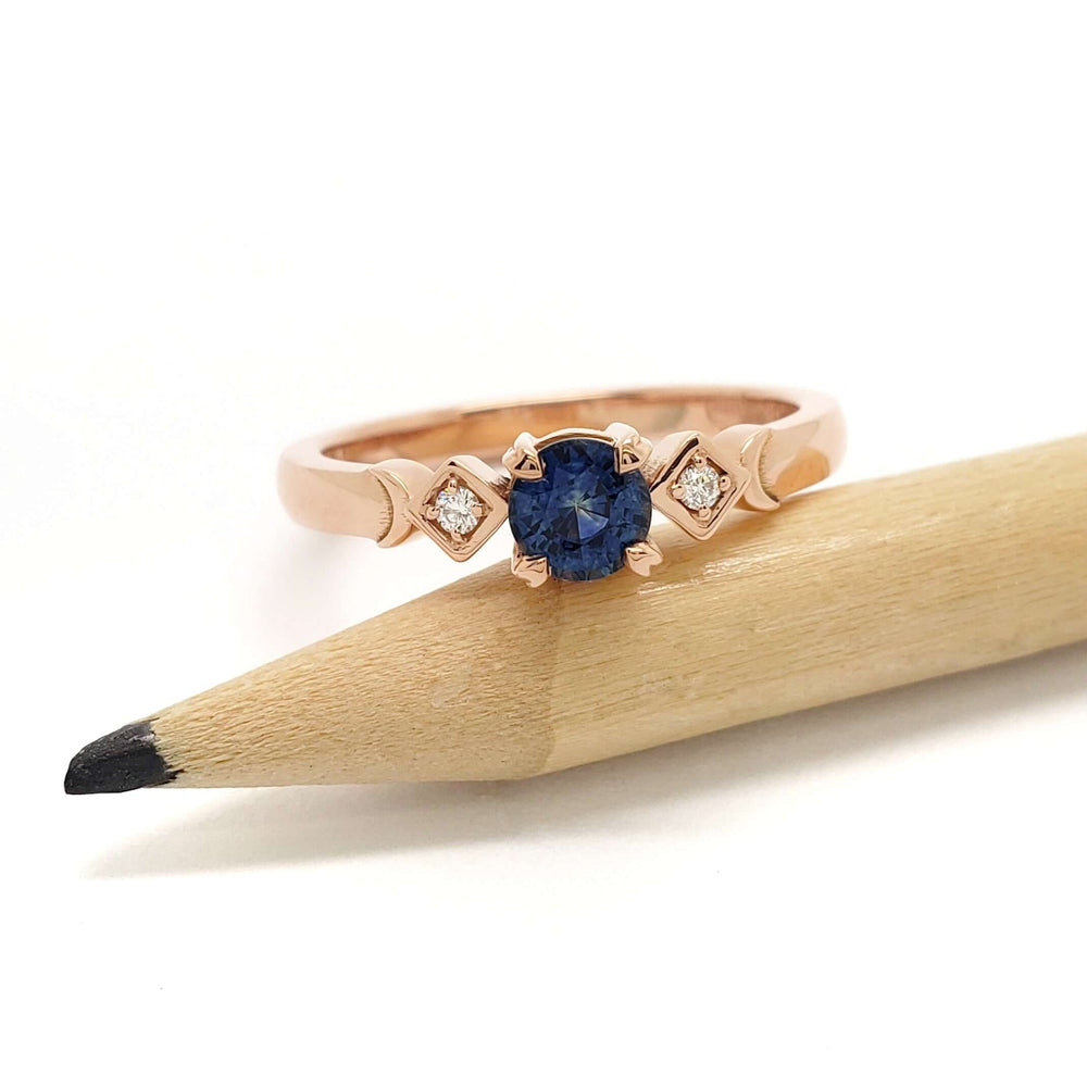Rose gold Montana sapphire and diamond ring displayed on a pencil for scale