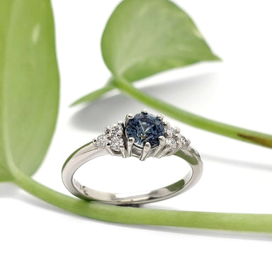 Montana sapphire and diamond 14k white gold ring displayed with green leaves