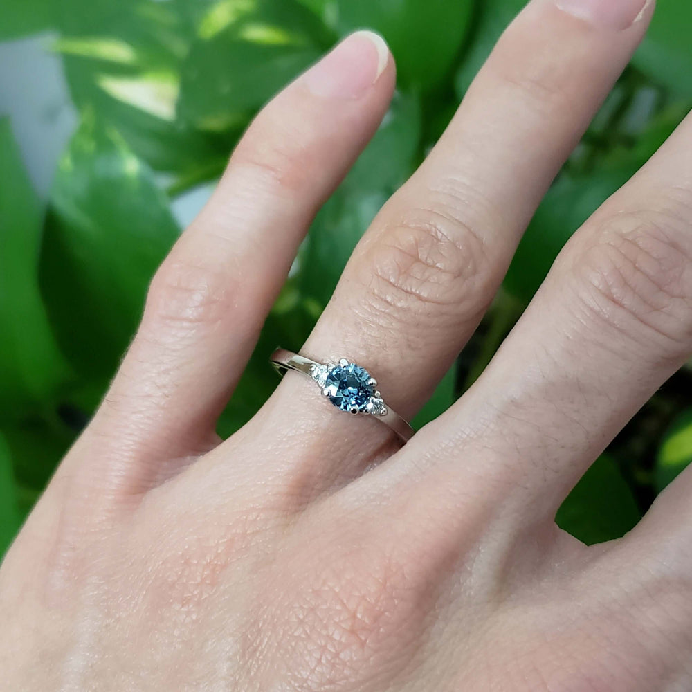 Montana sapphire and diamond white gold ring worn on hand, green background