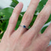 Montana sapphire and diamond white gold ring shown on hand, with green leaves in background