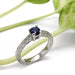 Montana sapphire and diamond engagement ring in white gold with engraved details, beside green plant