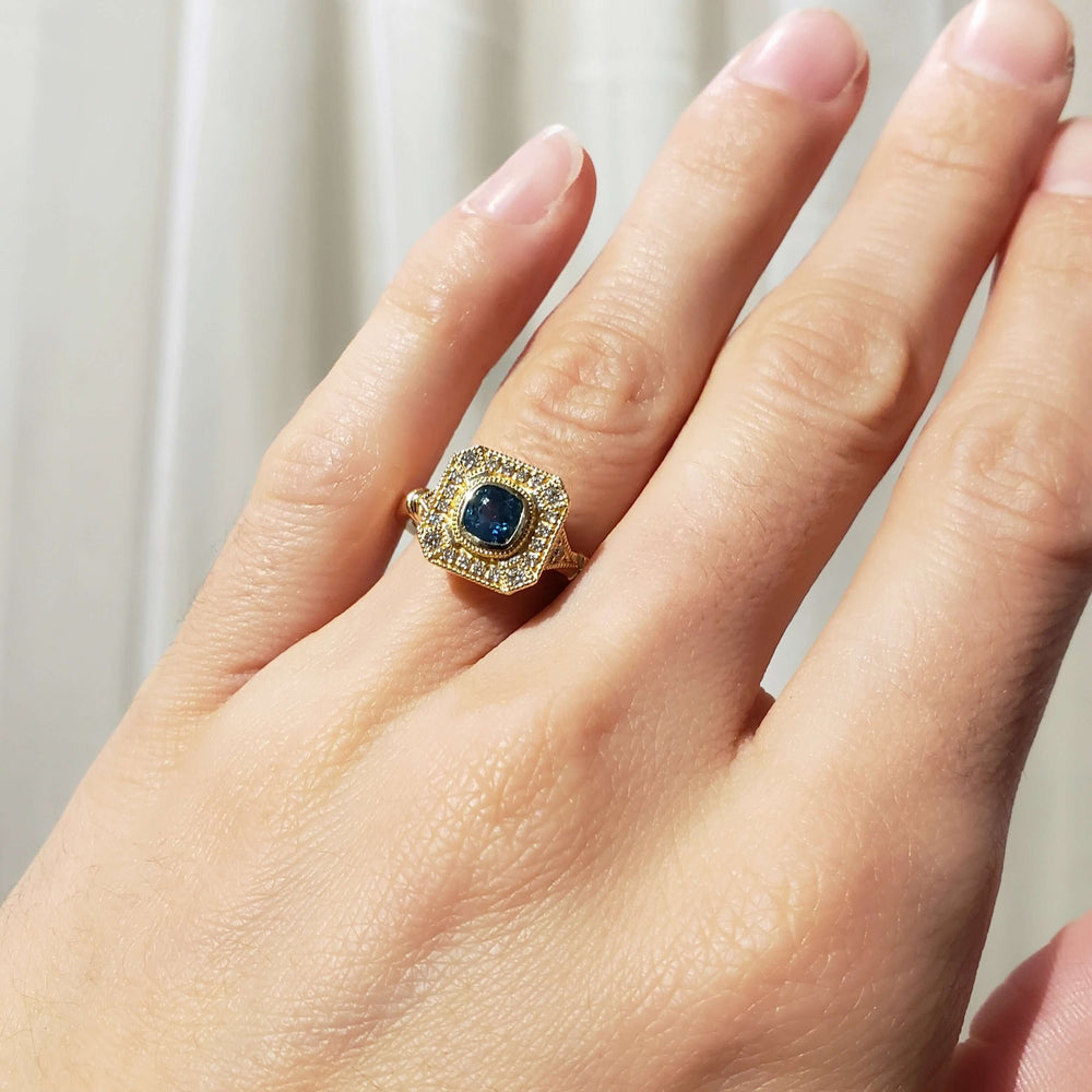 Montana sapphire and diamond yellow gold ring worn on a hand