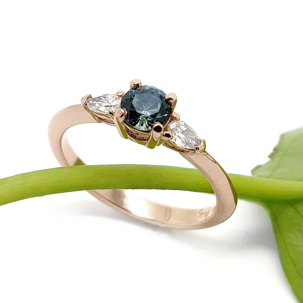 Montana sapphire and lab diamond engagement ring in rose gold, displayed on a green stem
