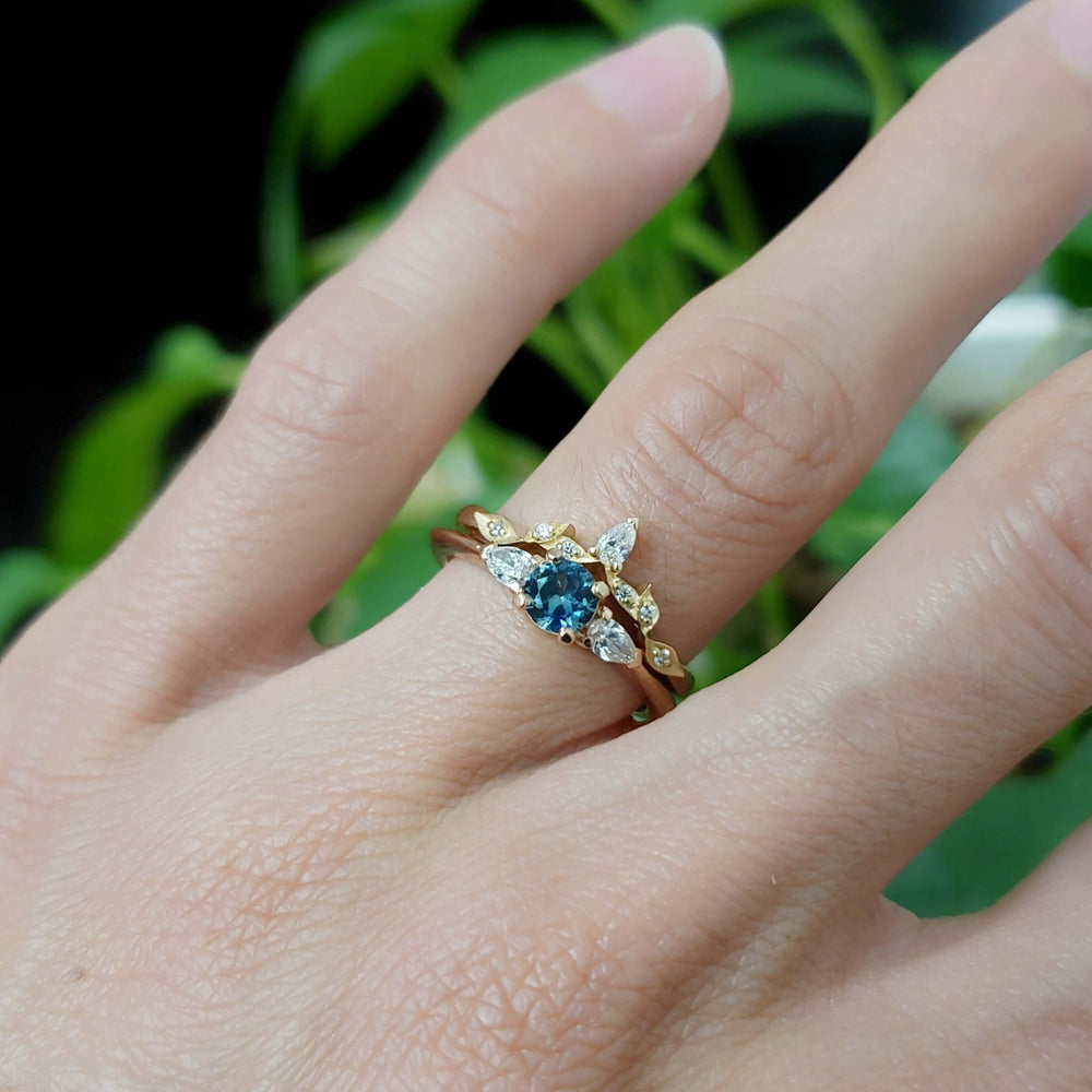 Montana sapphire and lab diamond ring stacked with a yellow gold diamond band on a hand