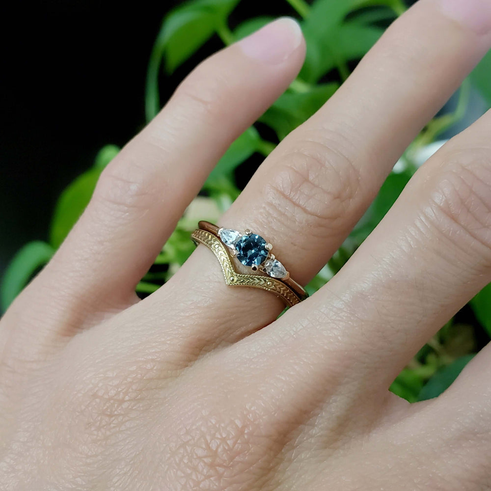 Montana sapphire and lab diamond ring paired with an engraved chevron band on a hand