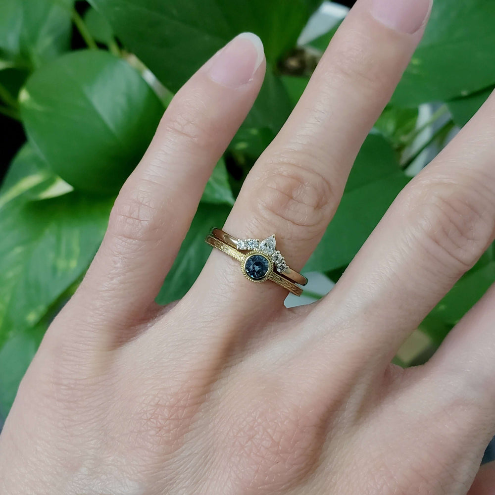 Montana sapphire and yellow gold ring stacked with two bands, worn on hand