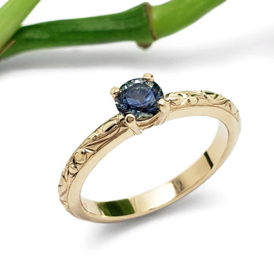 Montana sapphire engagement ring in engraved 14kt yellow gold, shown with bamboo