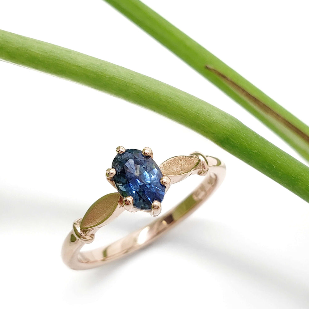 Montana sapphire engagement ring in rose gold with leaf accents, shown with green stem