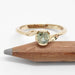 Montana sapphire engagement ring in yellow gold with leaf motif, shown beside pencil