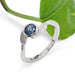 White gold Montana sapphire leaf ring shown with green leaf background