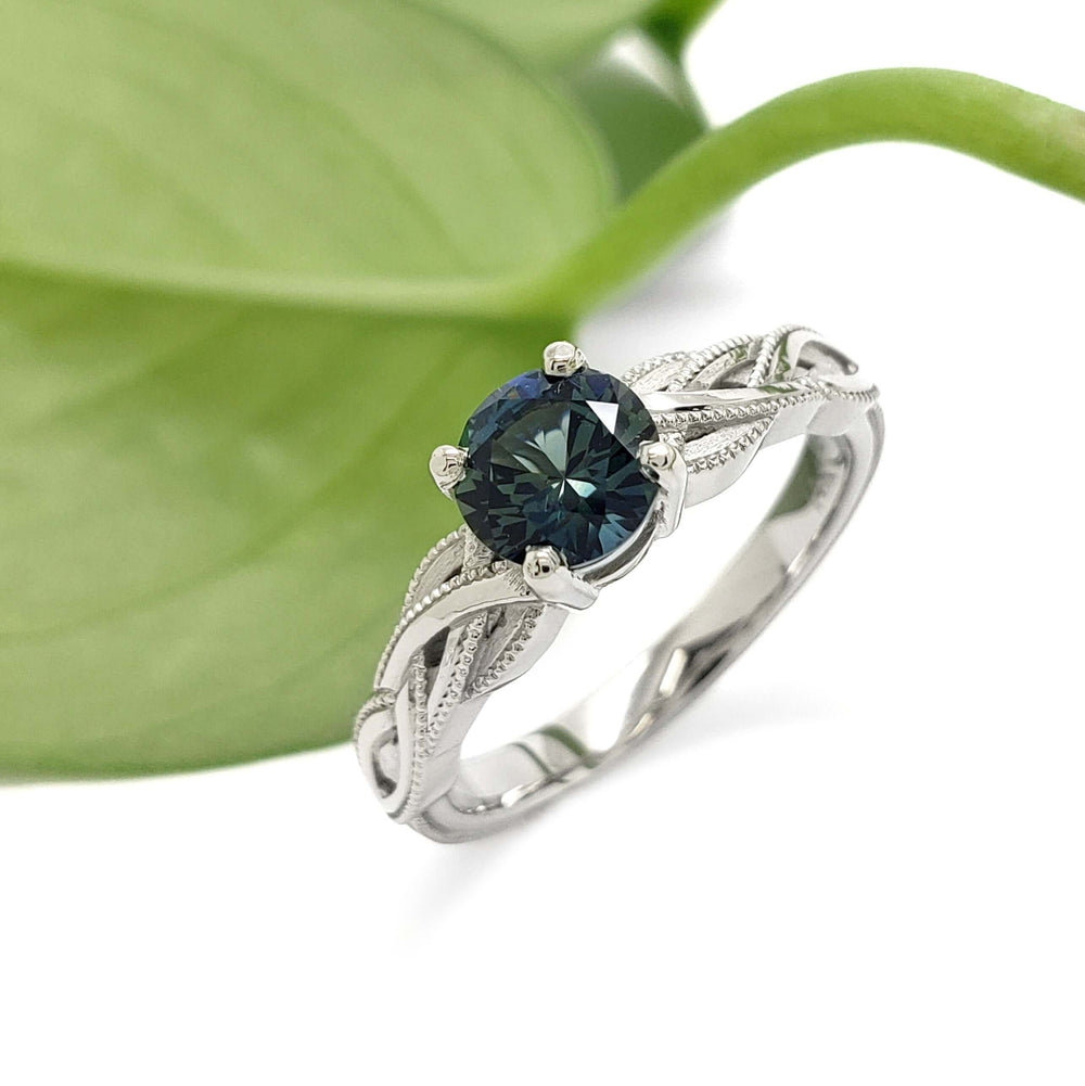 14kt white gold Montana sapphire ring with woven millgrain band, shown with green leaf