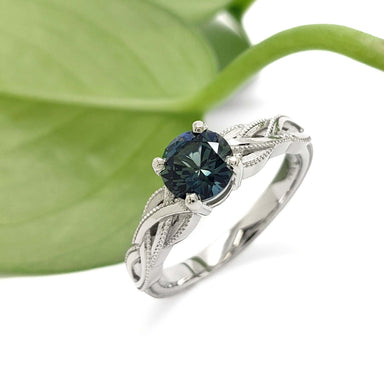 14kt white gold Montana sapphire ring with woven millgrain band, shown with green leaf