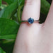 Montana sapphire solitaire ring in white gold shown on a hand with green leaves