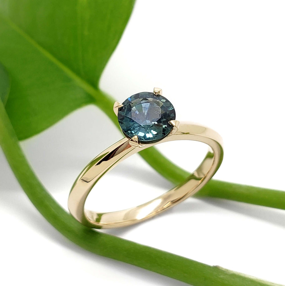 Montana sapphire solitaire ring in yellow gold, displayed with green leaf