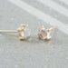 14kt yellow gold moonstone cabochon stud earrings shown on a textured surface