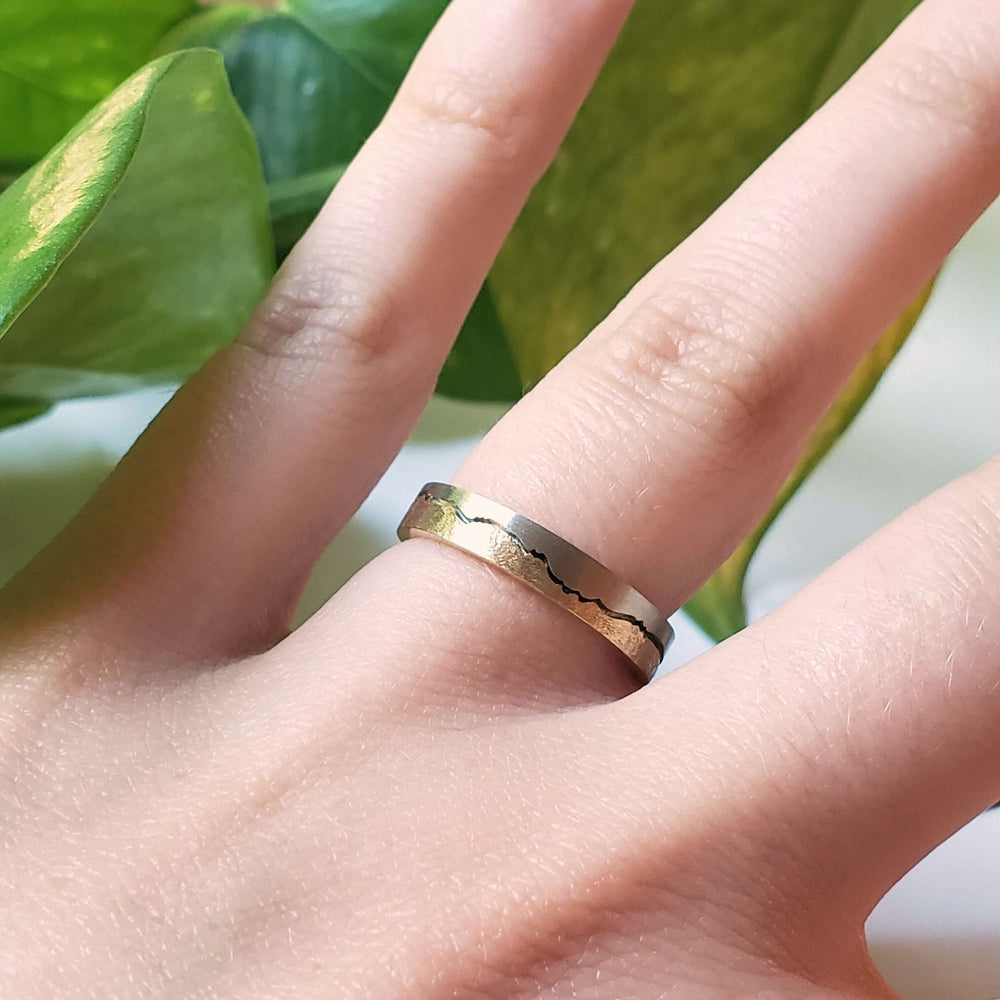 Mountain range wedding ring in 14kt white and yellow gold shown on hand