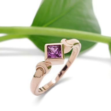 Nora Rose 14kt rose gold ring with purple sapphire, shown with green leaf background